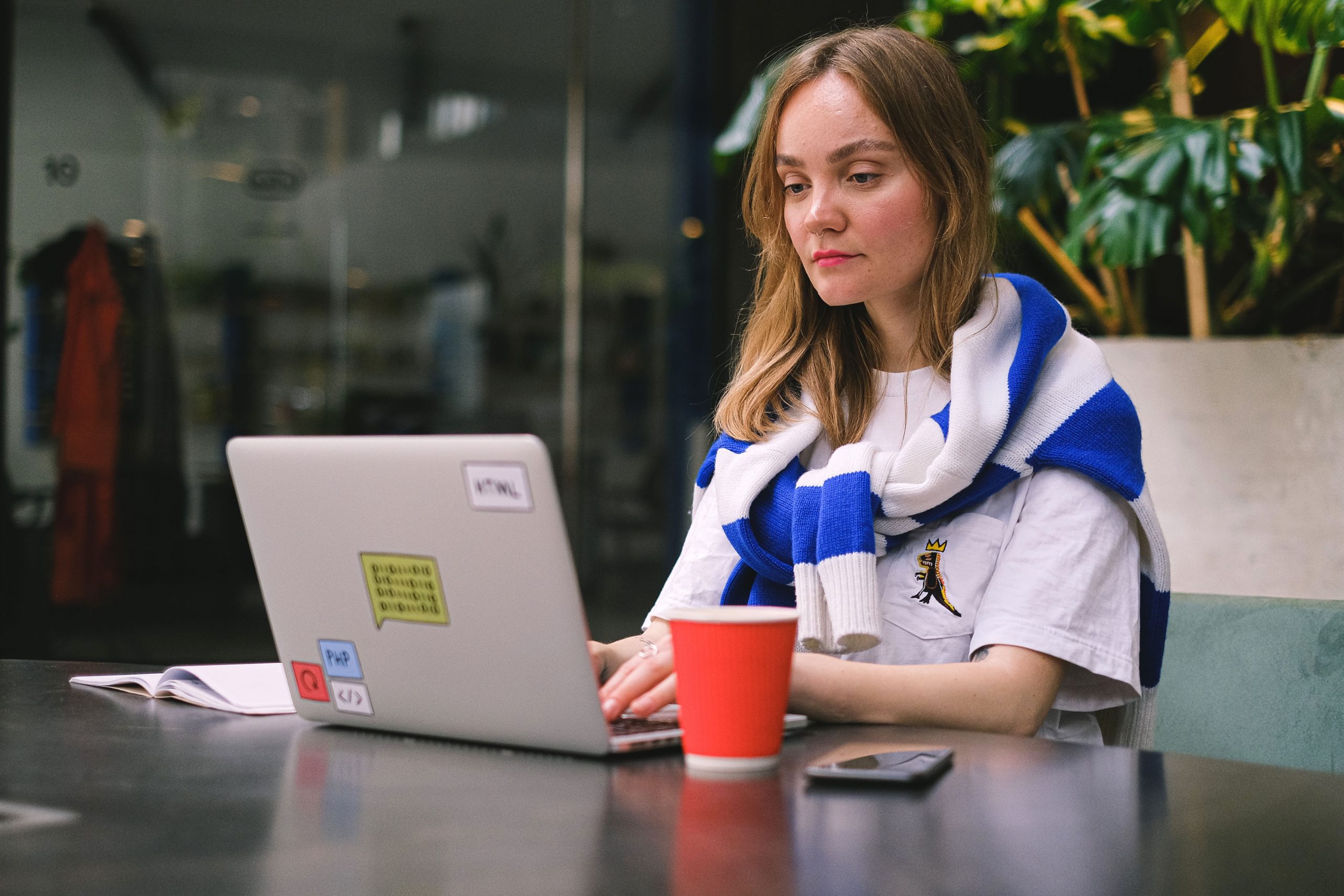 Jeune femme concentrée sur son travail freelance dans un café moderne, avec ordinateur portable