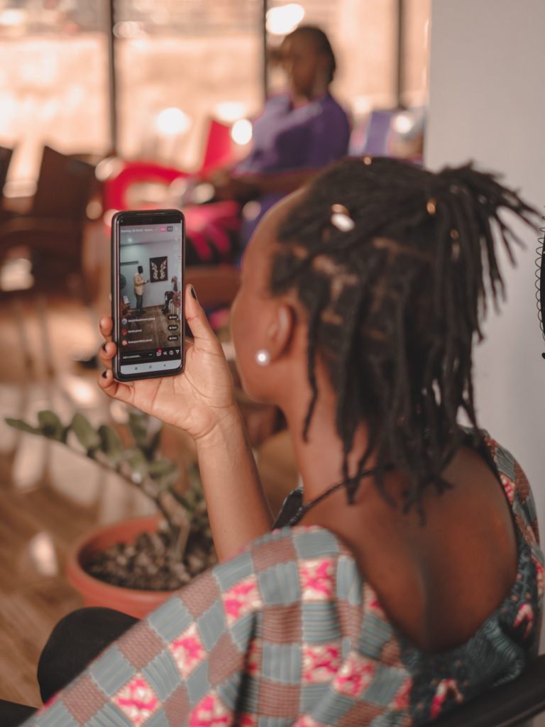 Femme scrollant sur son smartphone dans un intérieur cosy, réseaux sociaux et affiliation