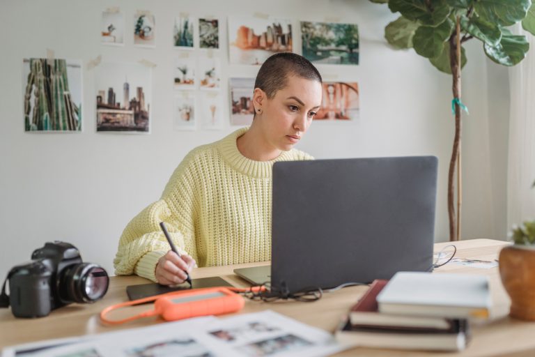 Jeune femme designer concentrée créant un template numérique sur ordinateur portable et tablette graphique