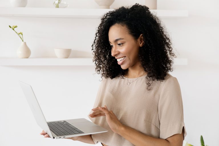 Femme souriante travaillant sur son ordinateur portable dans un bureau moderne à domicile, mode de vie freelance