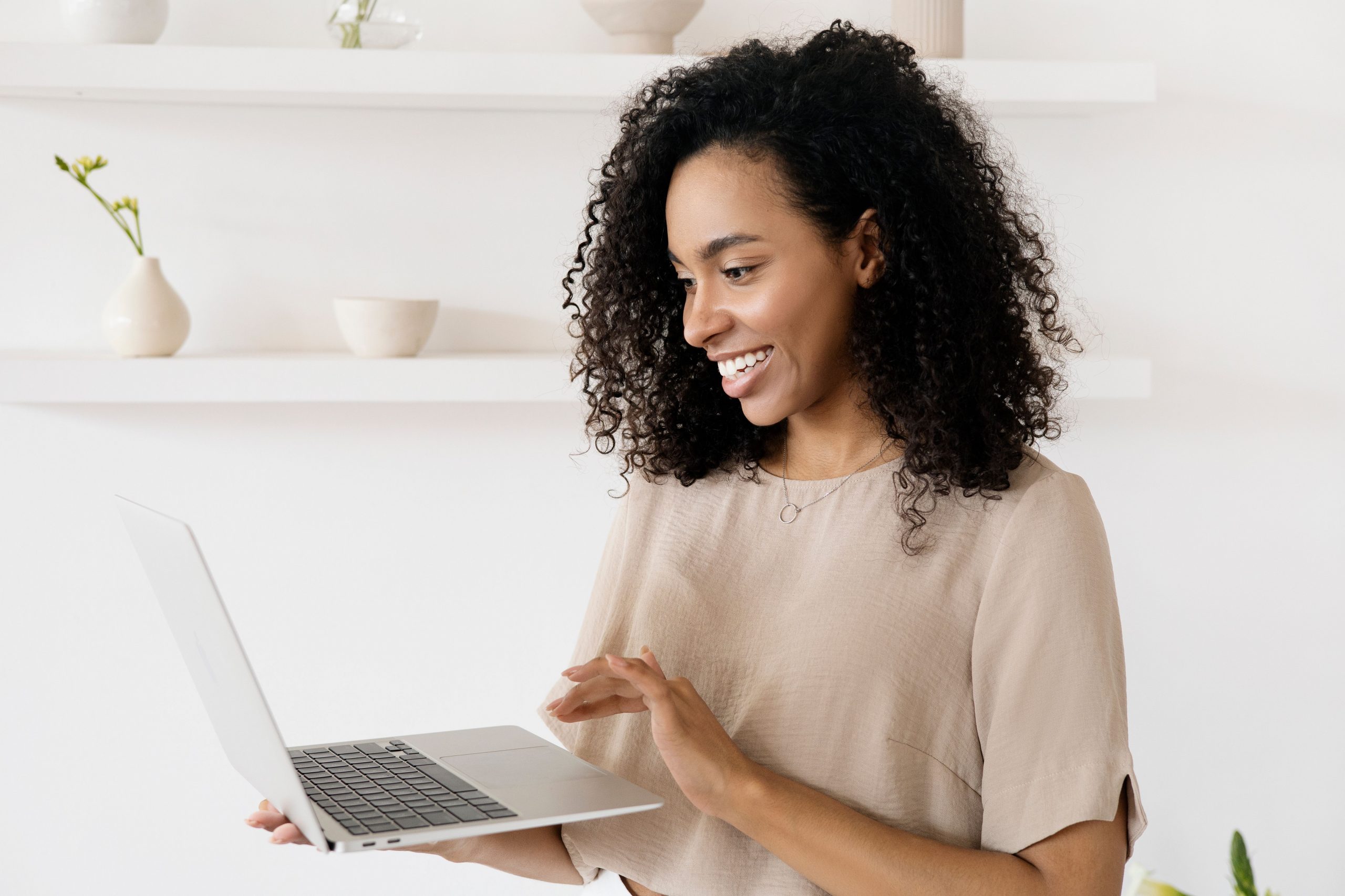 Femme souriante travaillant sur son ordinateur portable dans un bureau moderne à domicile, mode de vie freelance